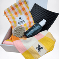 Dog grooming set with yellow / orange /pink checker towel, brush, dog shampoo and lick mat displayed in a  gift box 