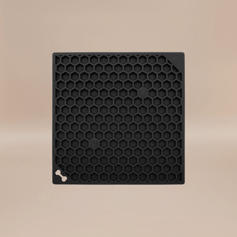Black honeycomb-patterned lick mat with a bone symbol on a beige background