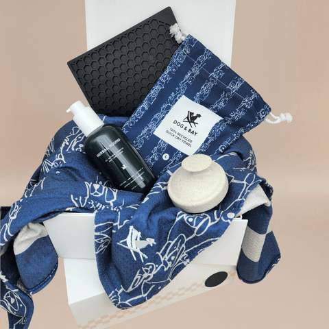 Dog grooming set with a blue towel, brush, dog shampoo and lick mat displayed in a  gift box 