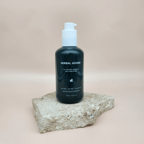 Bottle of Herbal Hound  2 in 1 shampoo  & conditioner sitting on a stone surface with a beige background