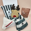 Close-up of premium dog gift box featuring ST ARGO natural dog treats, reversible Naughty/Nice bandana and Dock & Bay towel.